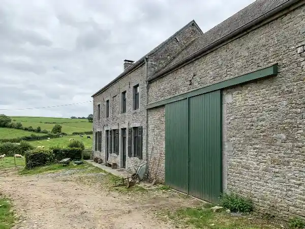 Fermette wallonne en pierre avec porte de grange et fenêtres au rez