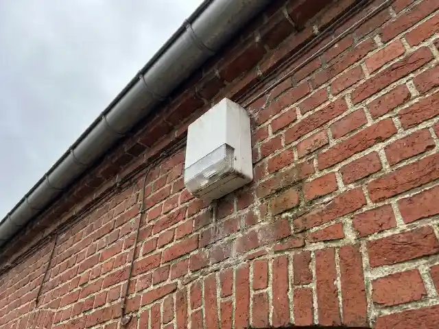 Sirène extérieure fixée en hauteur sur une façade en briques